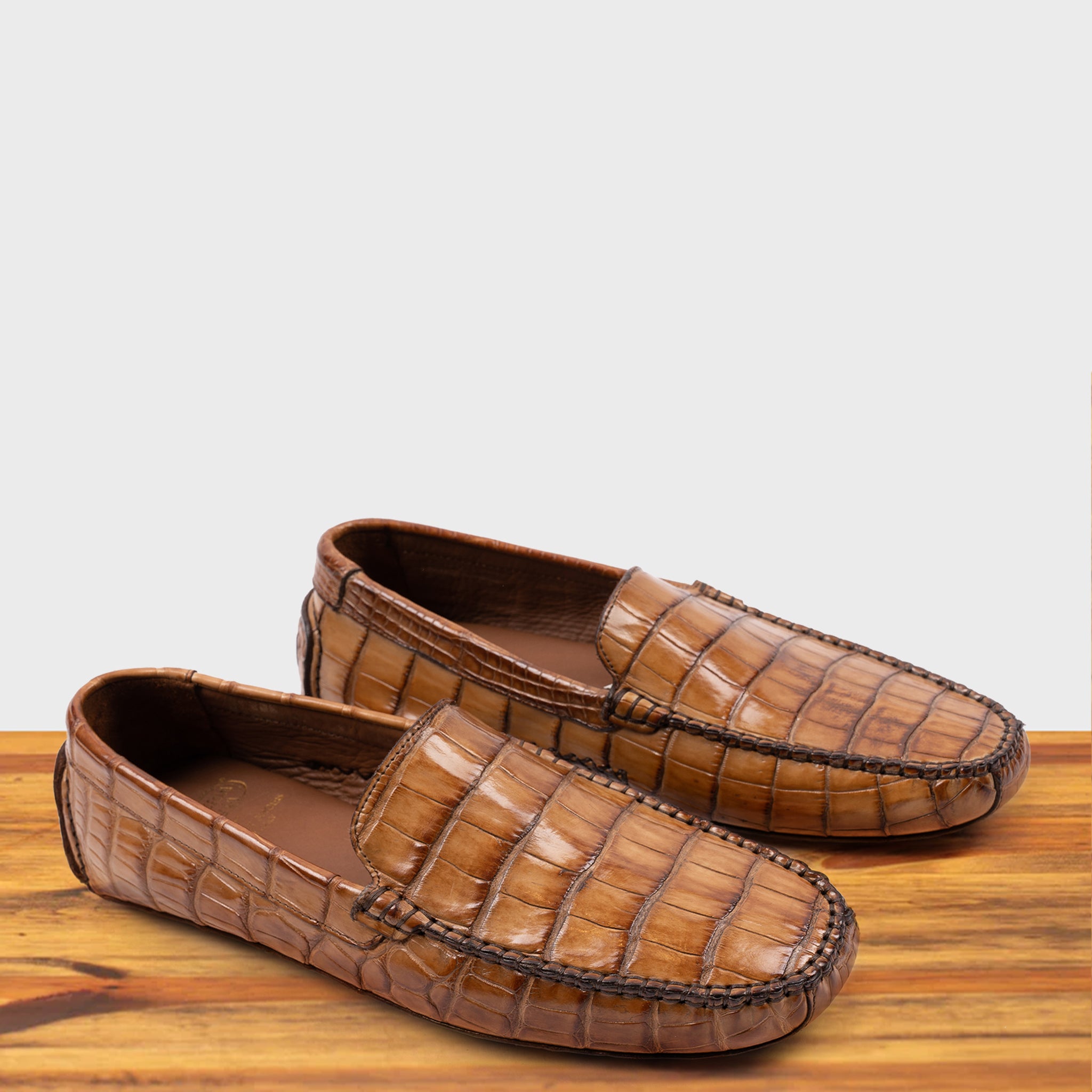 A Pair of Brick crocodile-patterned loafer on a wooden surface with a light gray background