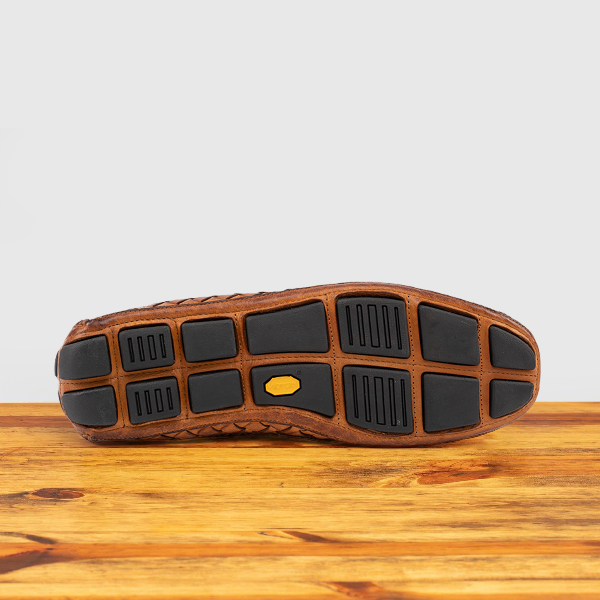 Outsole of Brick loafer shoe with woven pattern on a wooden surface