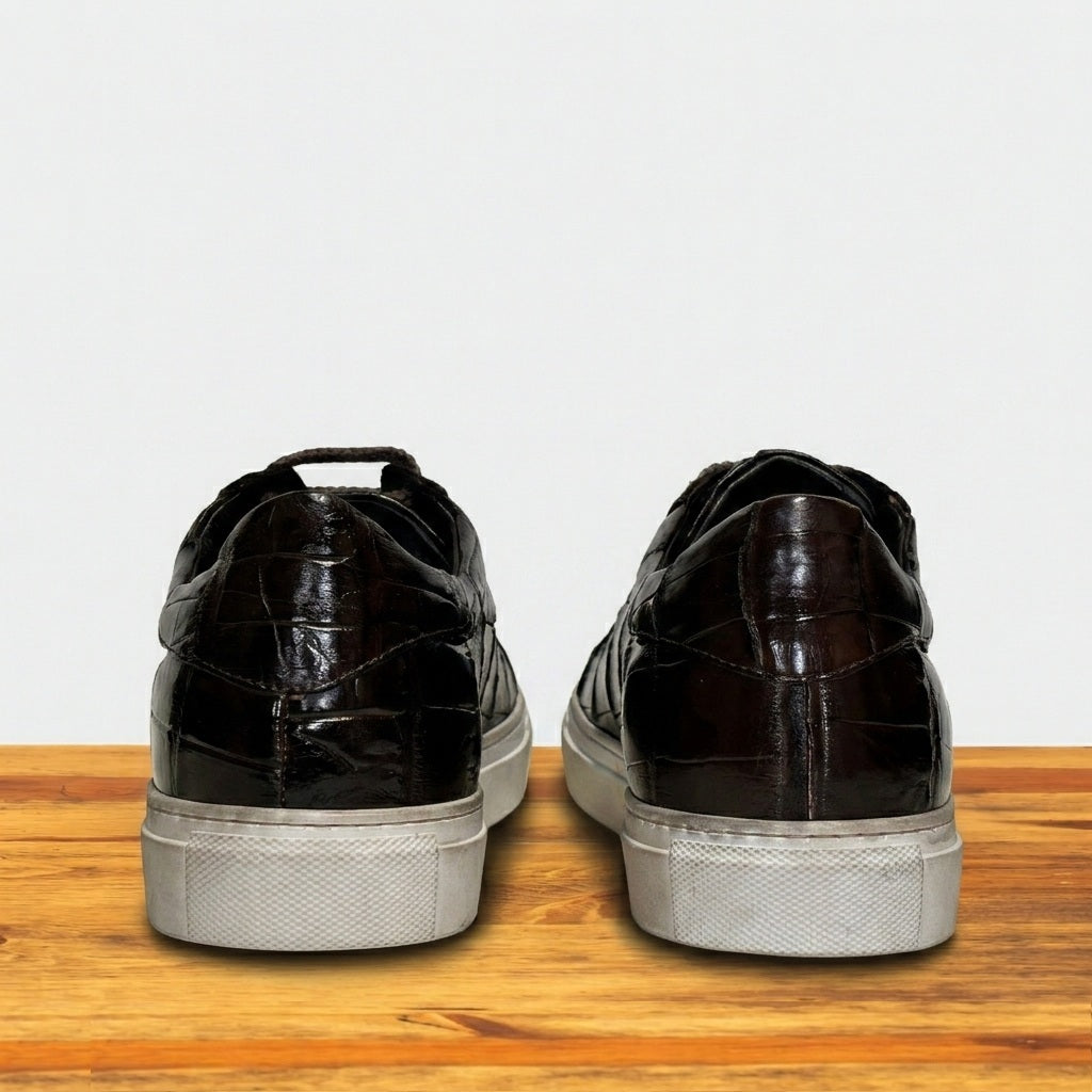 Black leather shoes with white soles on a wooden surface and light gray background