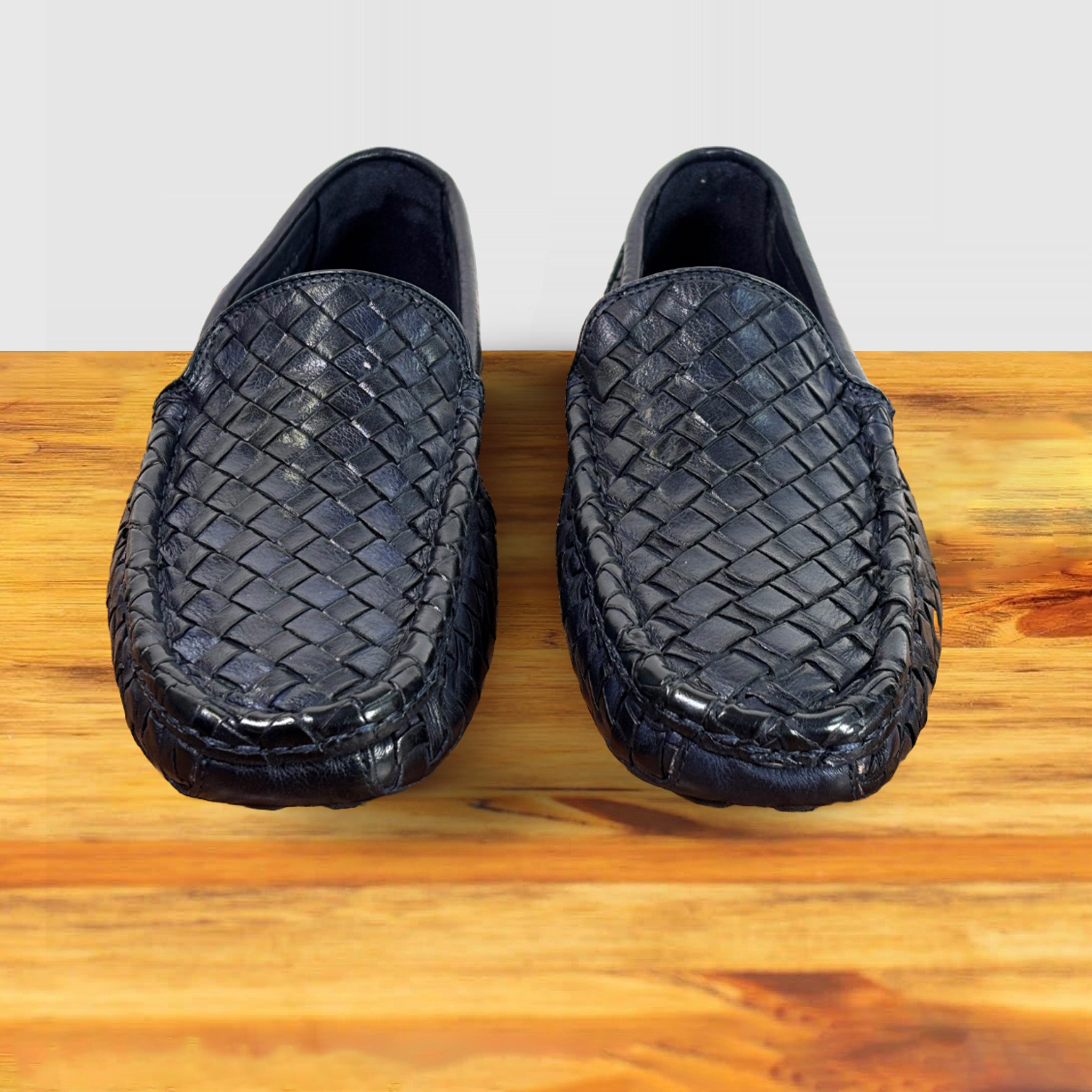Pair of Navy Blue loafer shoe with woven pattern on a wooden surface