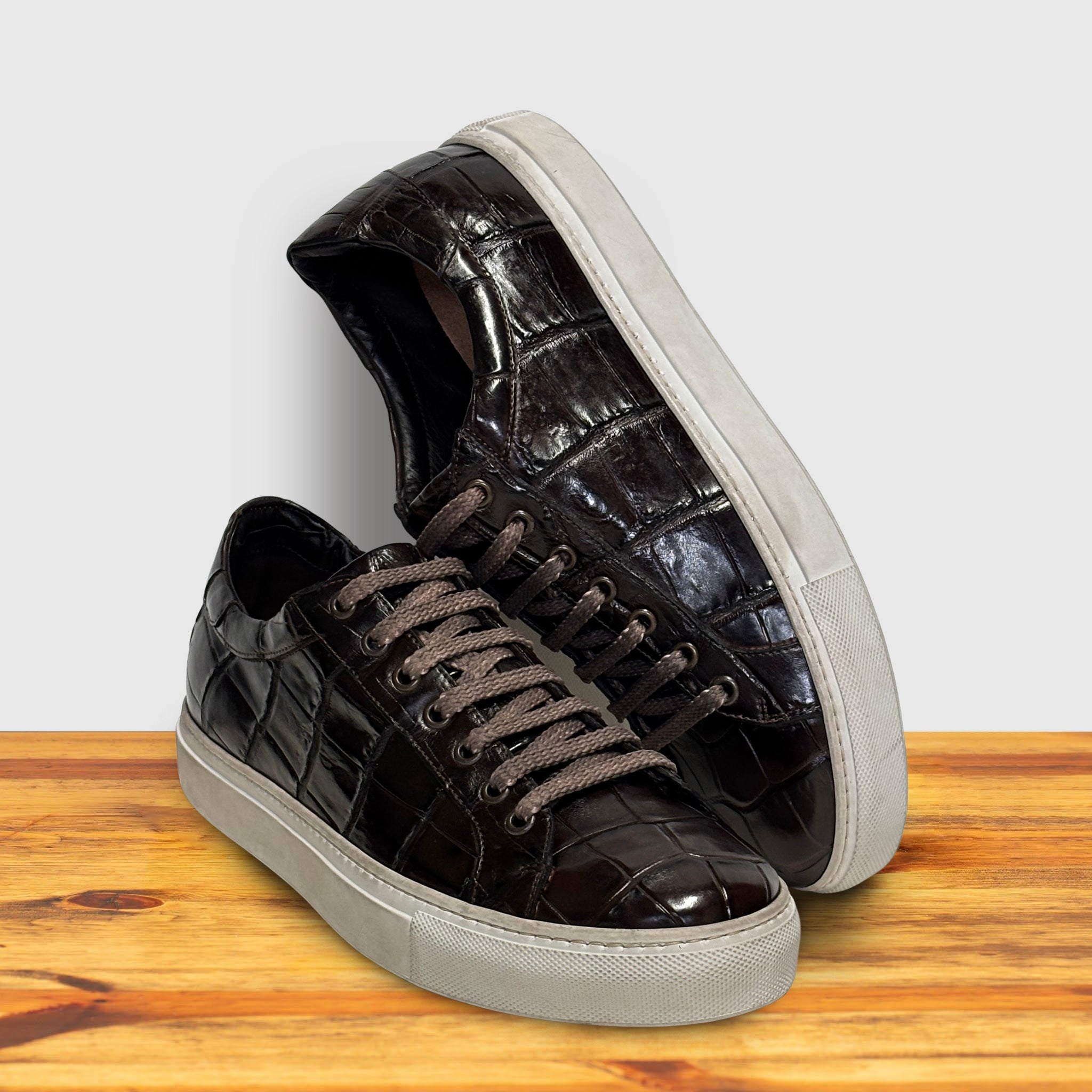 Dark Brown glossy sneakers with white soles on a wooden surface