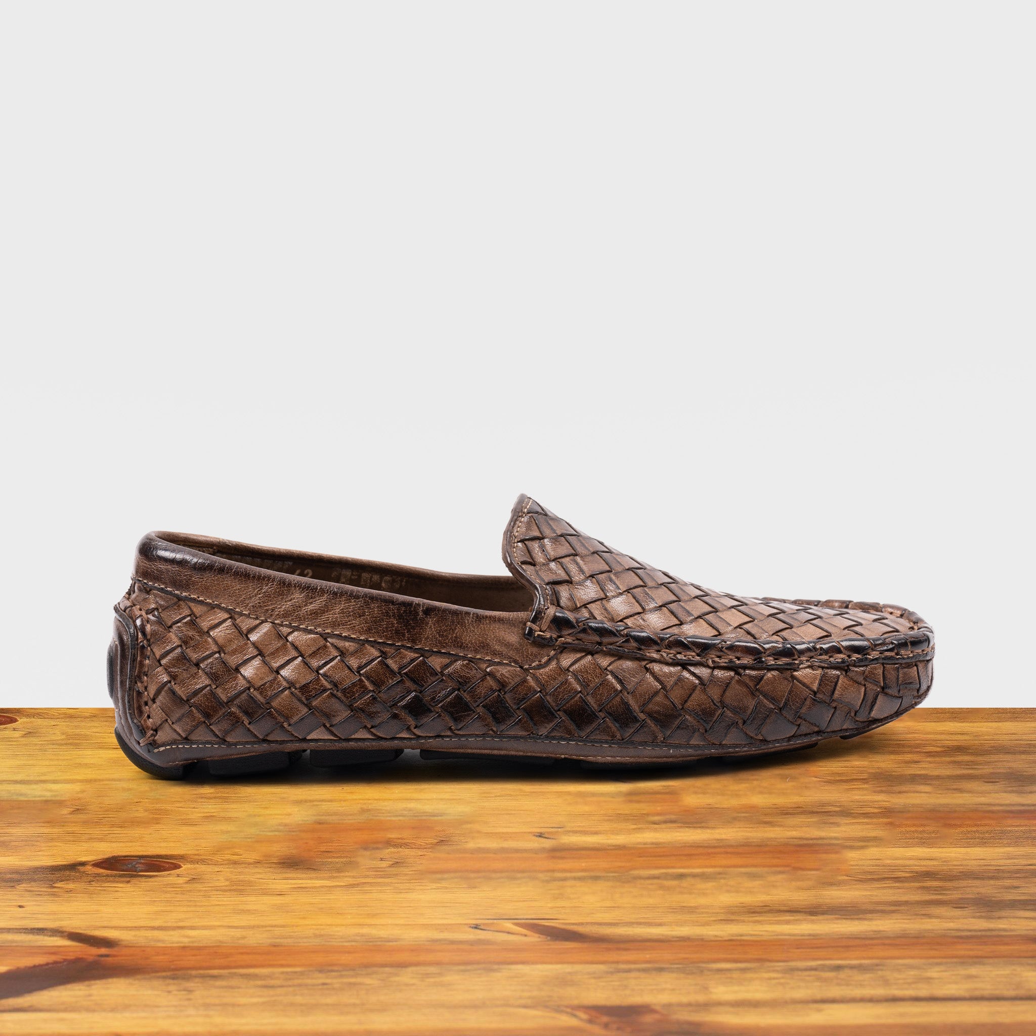 Moor loafer shoe with woven pattern on a wooden surface