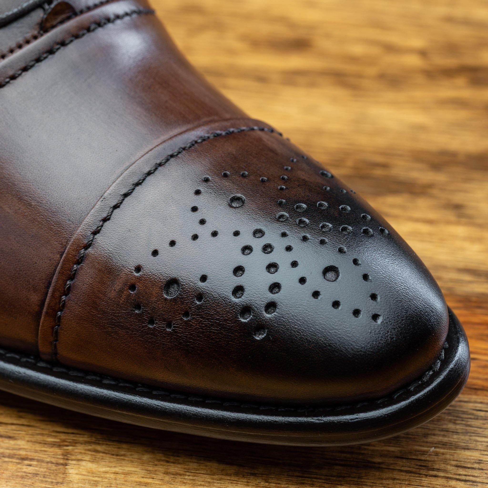 Close view of brown leather oxford dress shoes with a polished finish, on a wooden surface