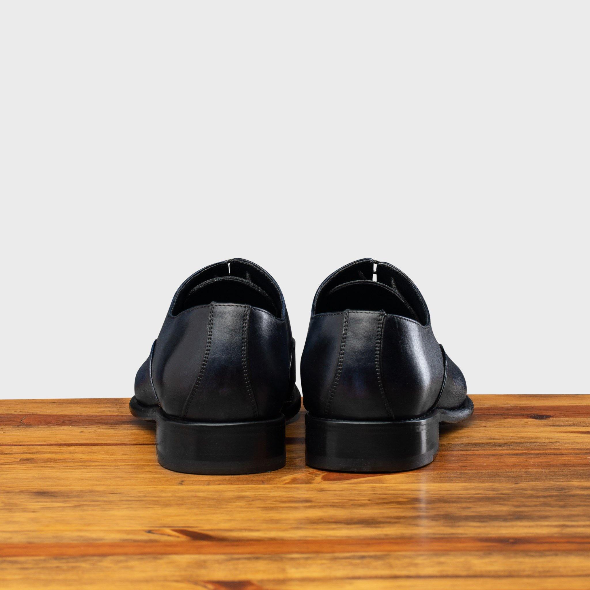 Back View of Blue leather dress shoe on a wooden surface with a white background