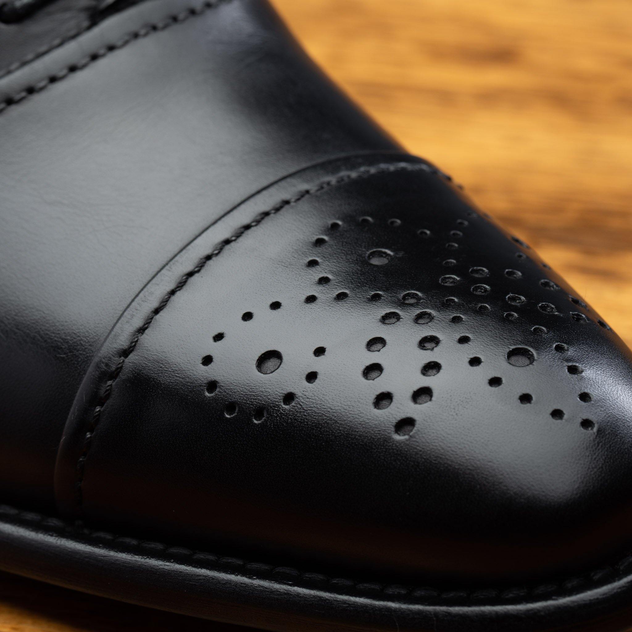 Close view of Black leather dress shoe on a wooden surface