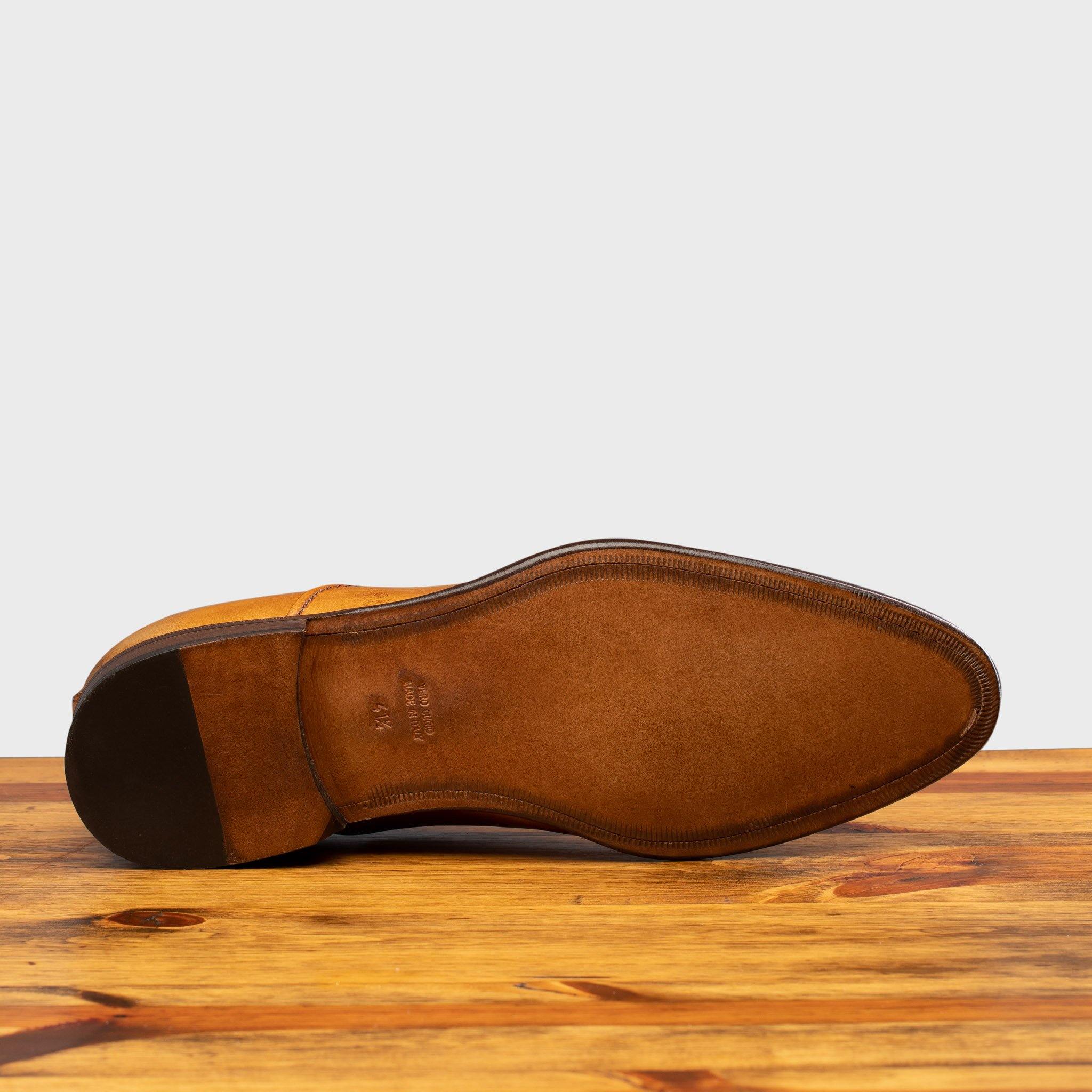 Outsole of Dark Caramel leather dress shoe on a wooden surface with a white background