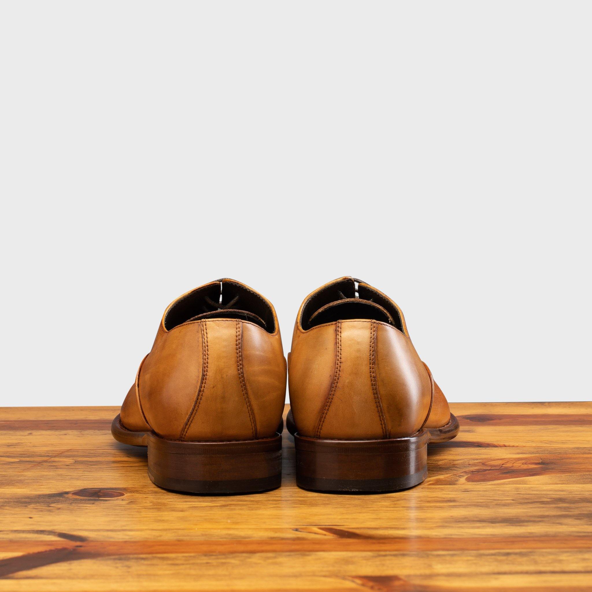 Back View of Dark Caramel leather dress shoe on a wooden surface with a white background