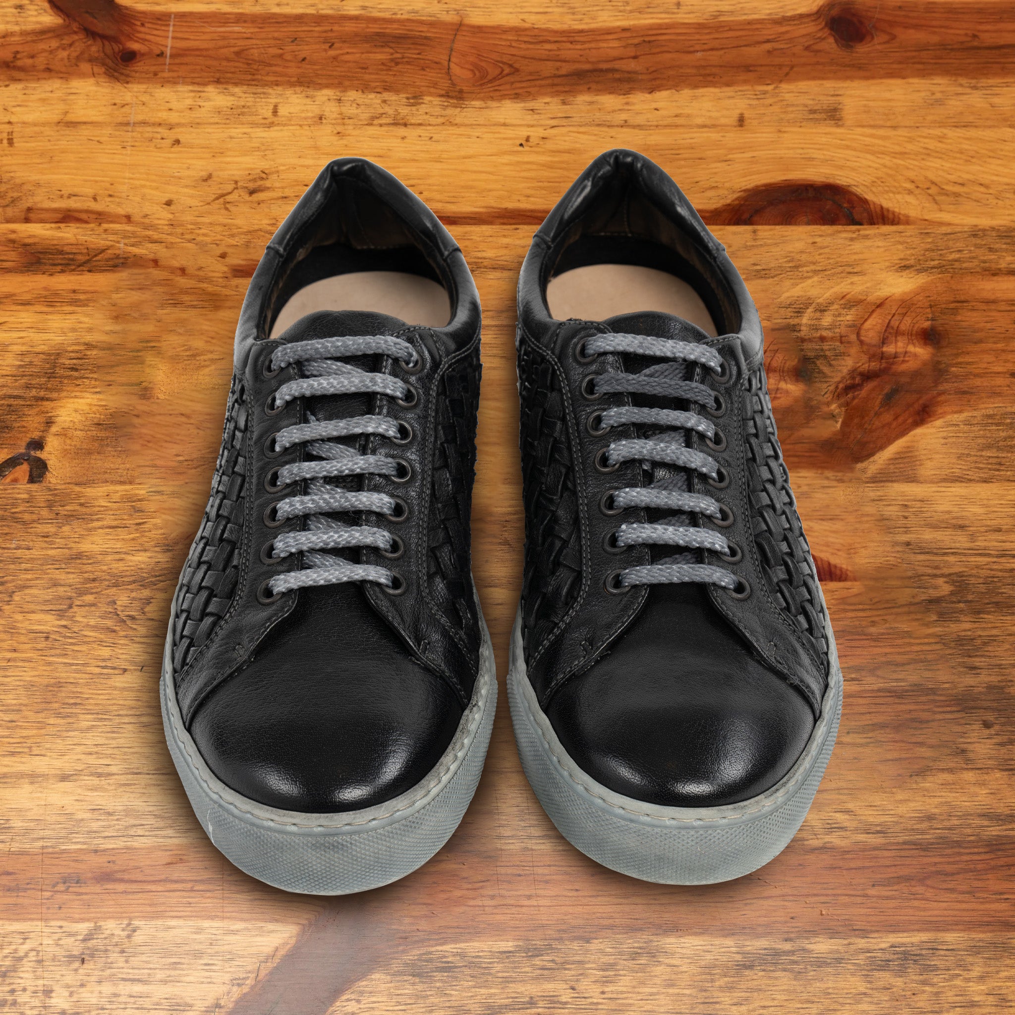 A Pair of Black woven sneaker on a wooden surface