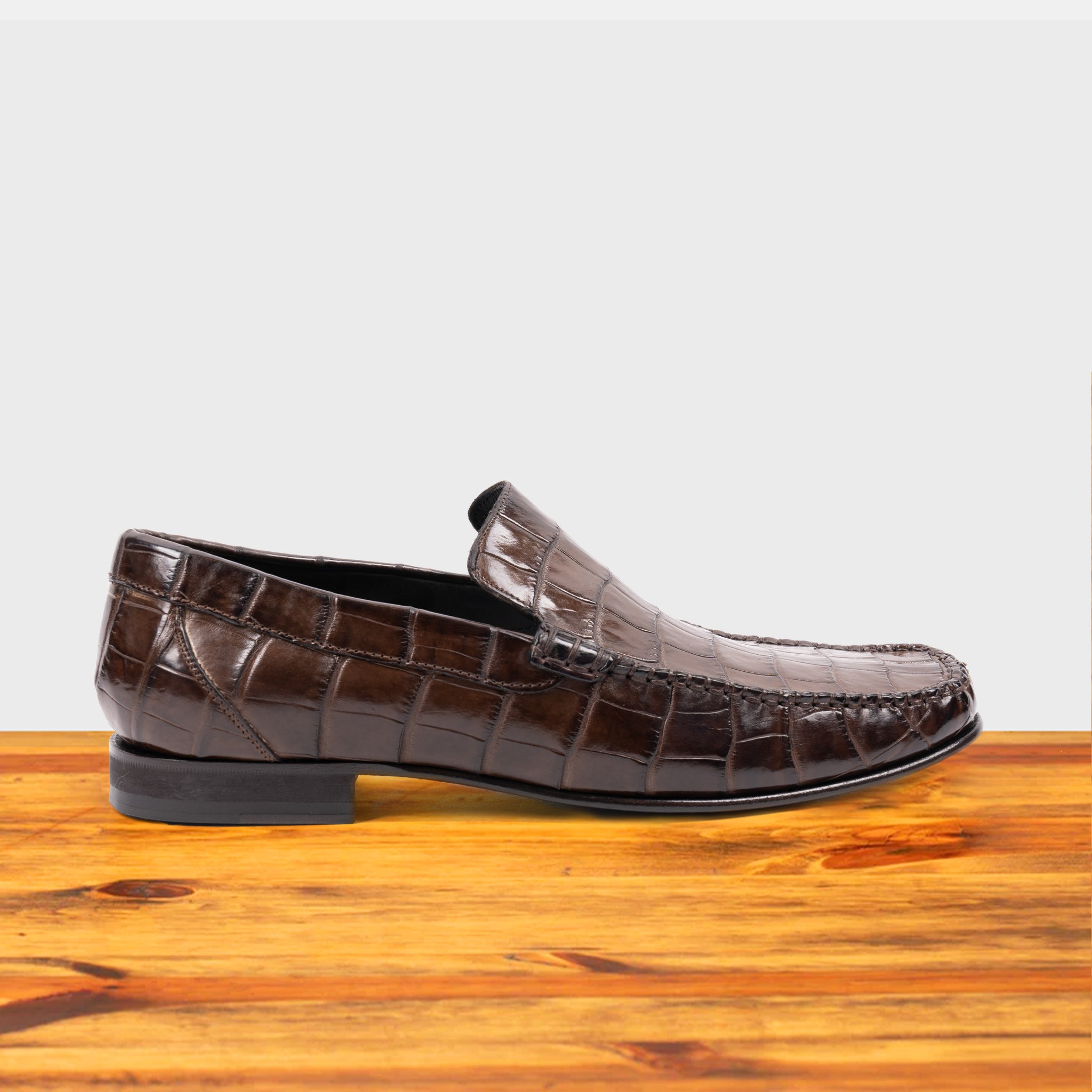Moor crocodile-patterned loafer on a wooden surface with a light gray background