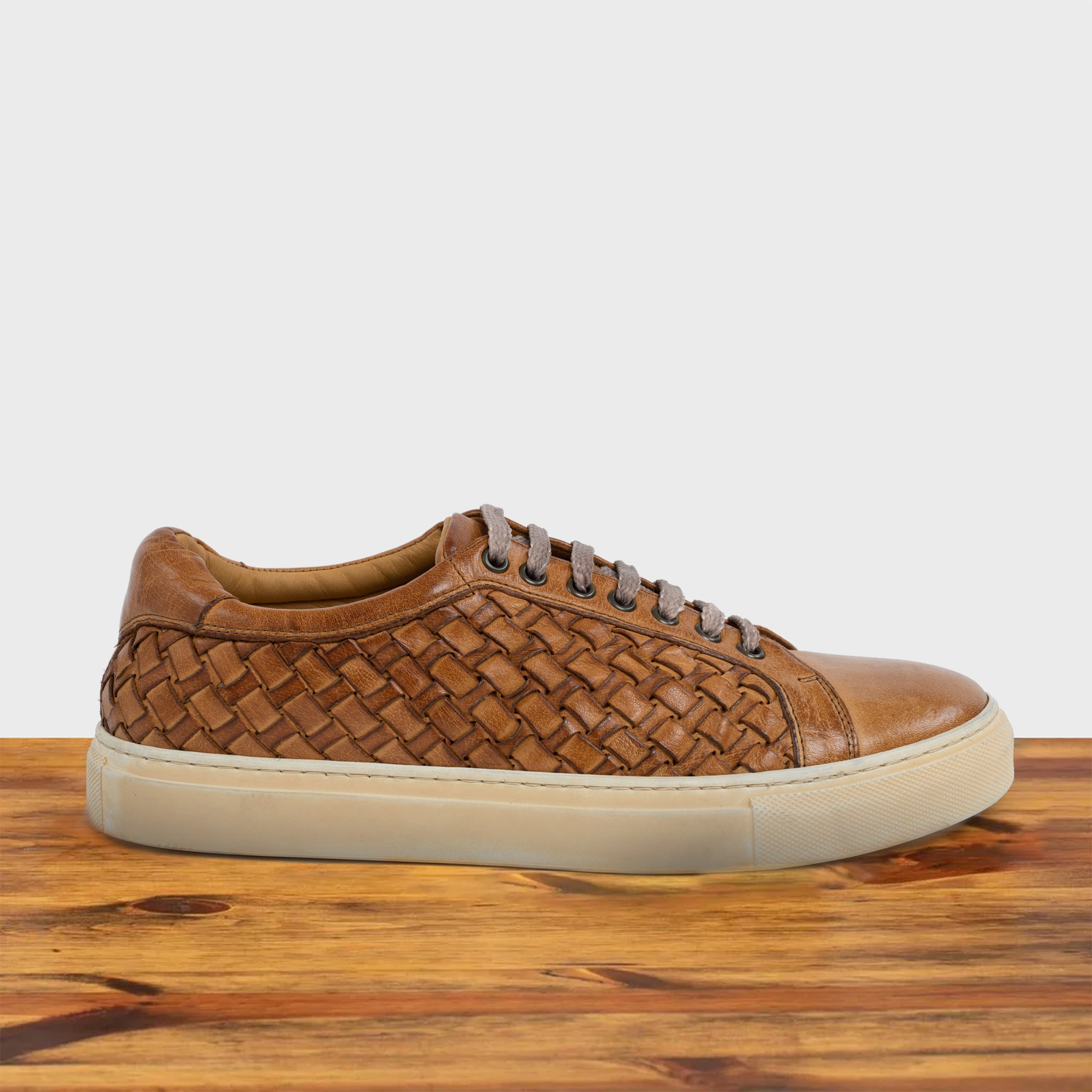 Brick woven sneaker on a wooden surface with a light gray background