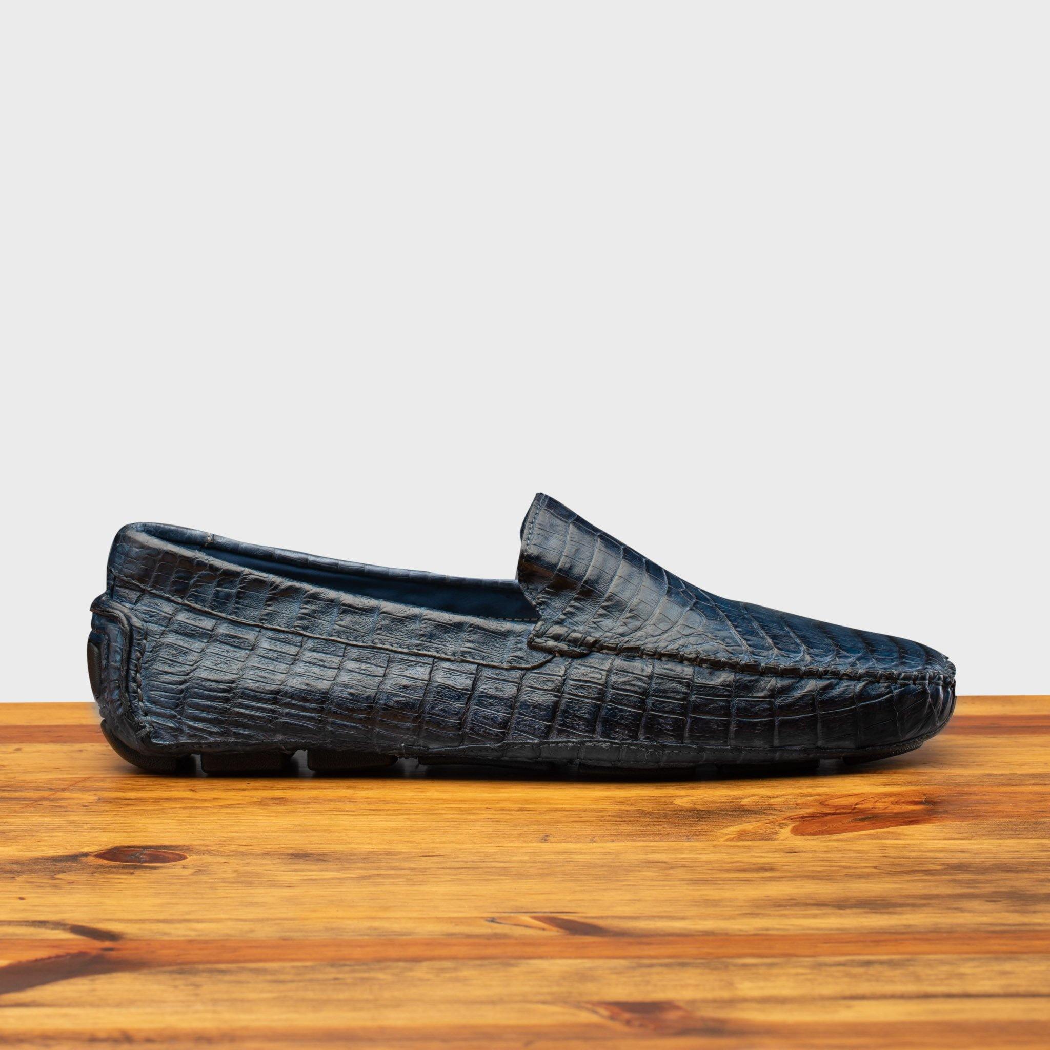 Denim crocodile-patterned loafer on a wooden surface with a light gray background