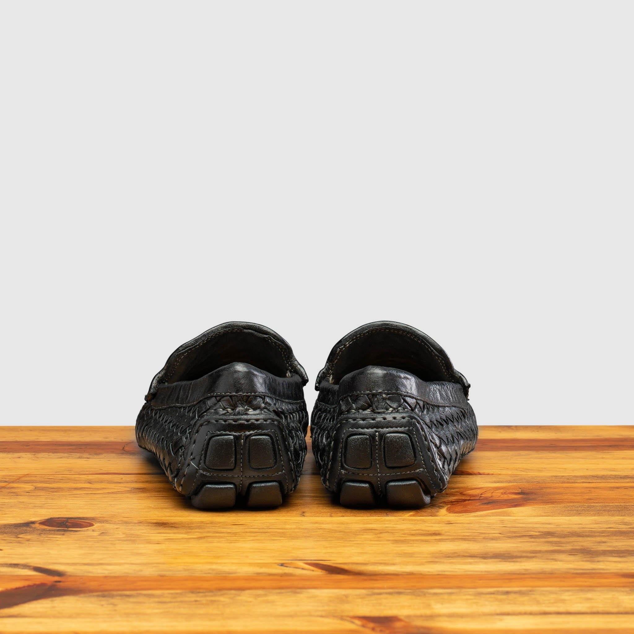 Pair of Black loafer shoe with woven pattern on a wooden surface