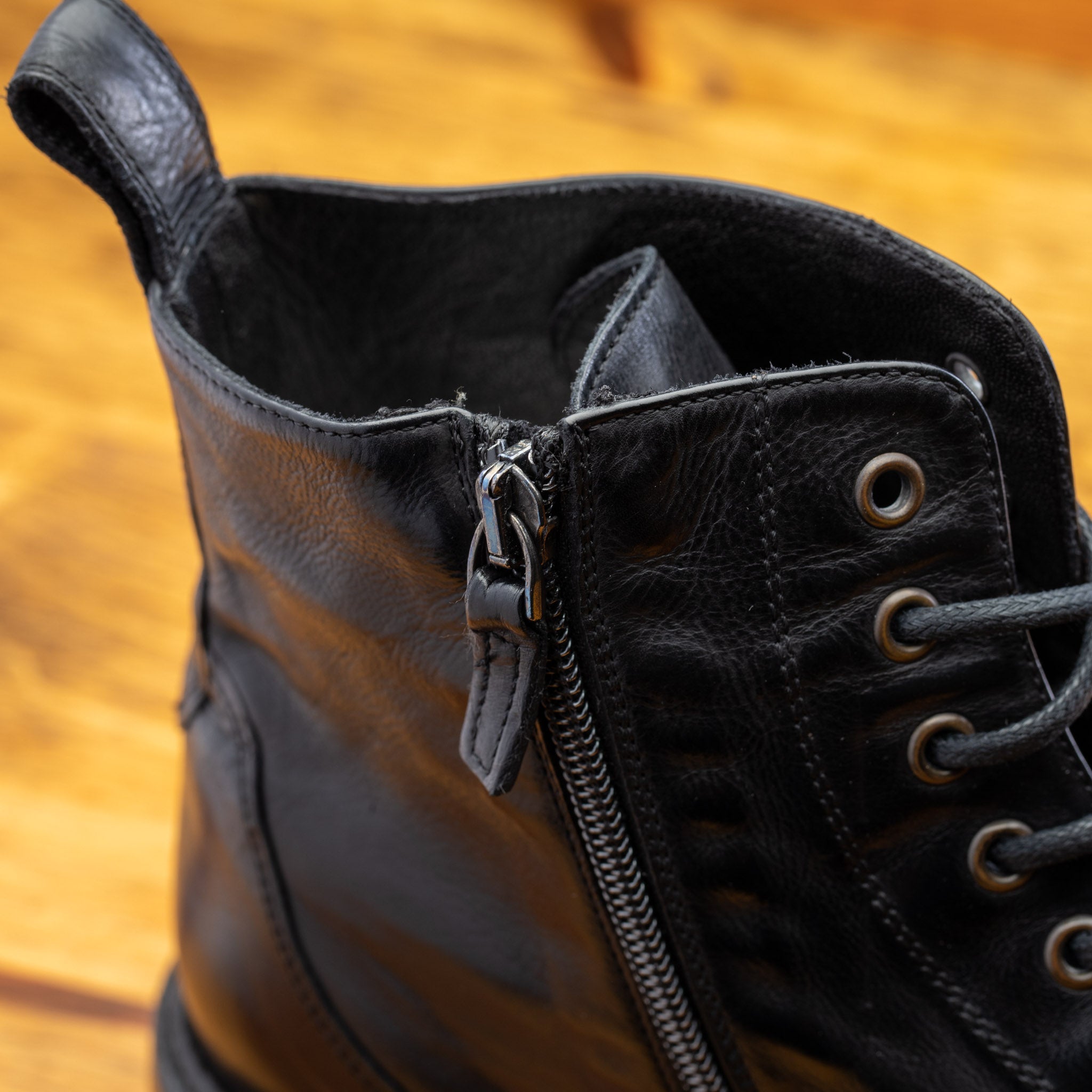 Close view of Black leather boot on a wooden surface