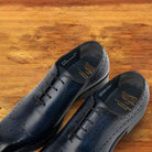 A Pair of Black wholecut dress shoe on a wooden surface
