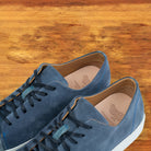Blue suede sneaker with white sole on a wooden surface