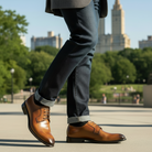 Person wearing brown dress shoes with a blurred cityscape background