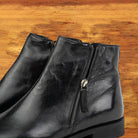 A Pair of Black leather ankle boot with a zipper on a wooden surface