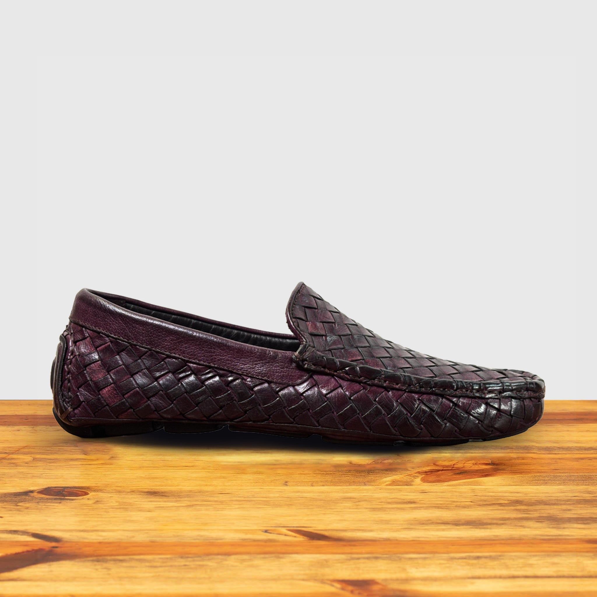 Merlot loafer shoe with woven pattern on a wooden surface