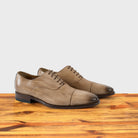 A Pair of Straw leather shoe on a wooden surface with a light gray background