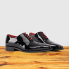 Pair of Black patent leather shoe with red laces on a wooden surface