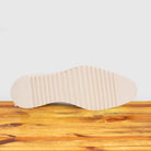 Outsole of White shoe on a wooden surface with a light gray background