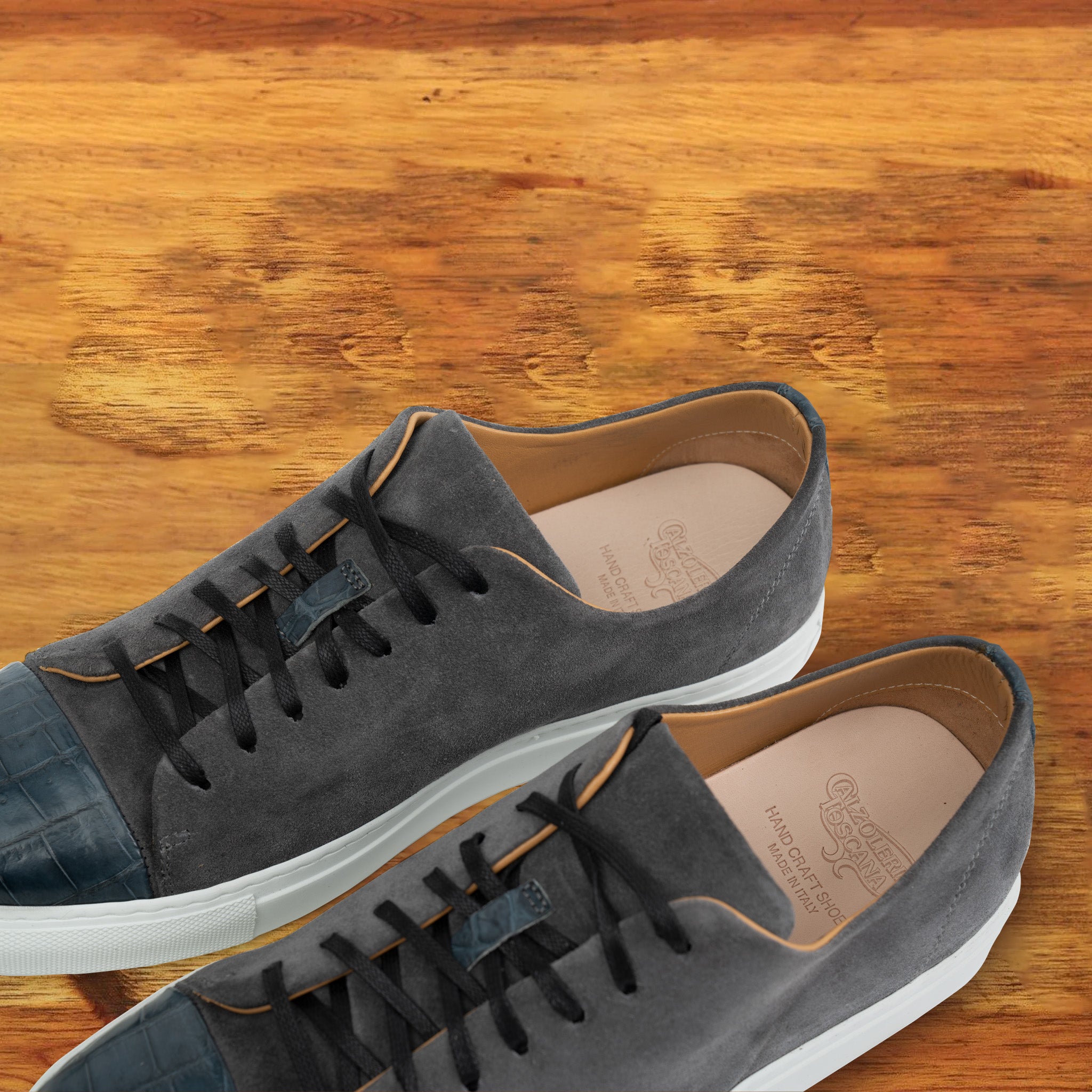 A Pair of Gray suede sneaker with white sole on a wooden surface