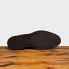 Outsole of the Brown suede boots on a wooden surface with a light gray background