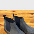 Close view of Stone leather Chelsea boots on a wooden surface
