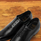 A Pair of Black wholecut dress shoe on a wooden surface