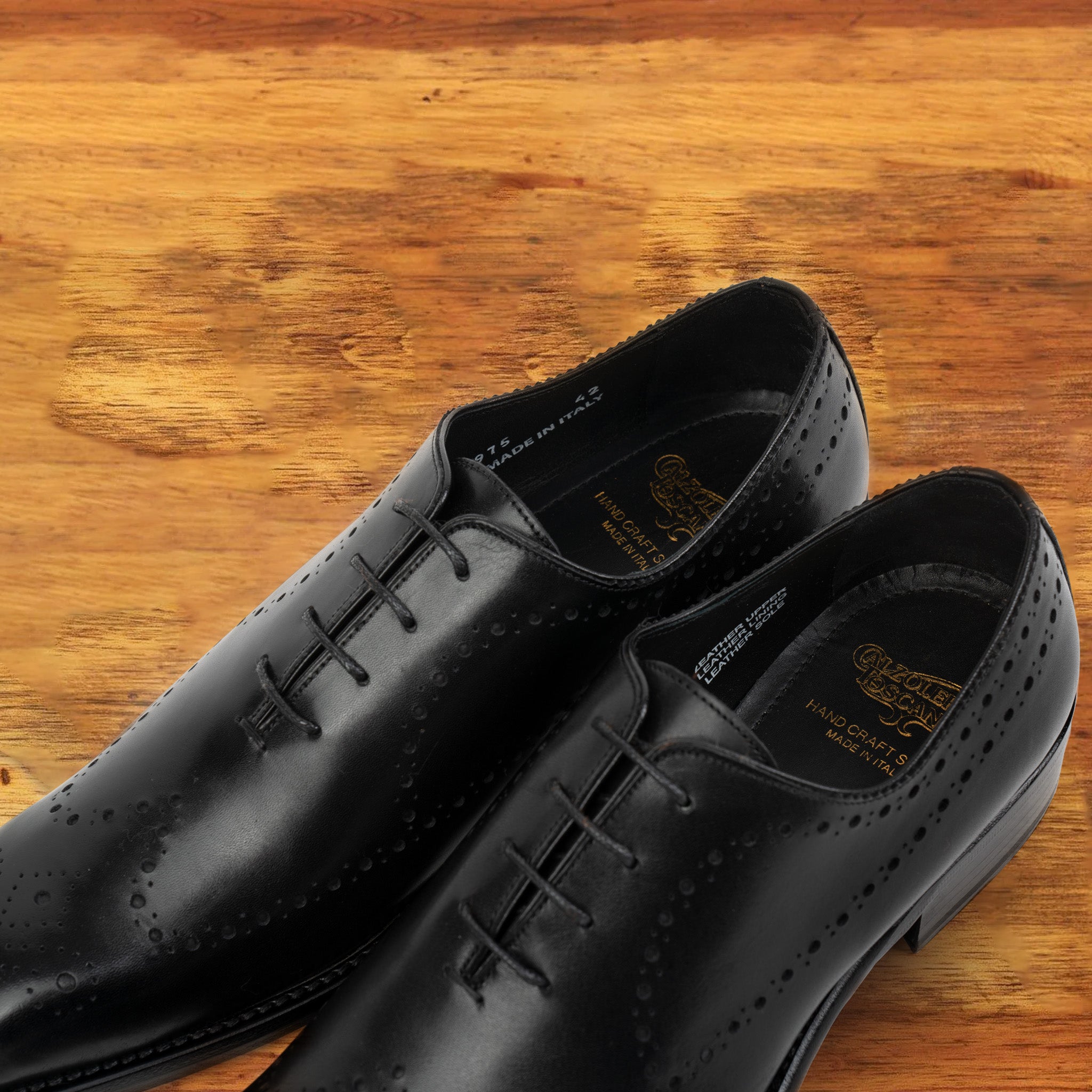 A Pair of Black wholecut dress shoe on a wooden surface