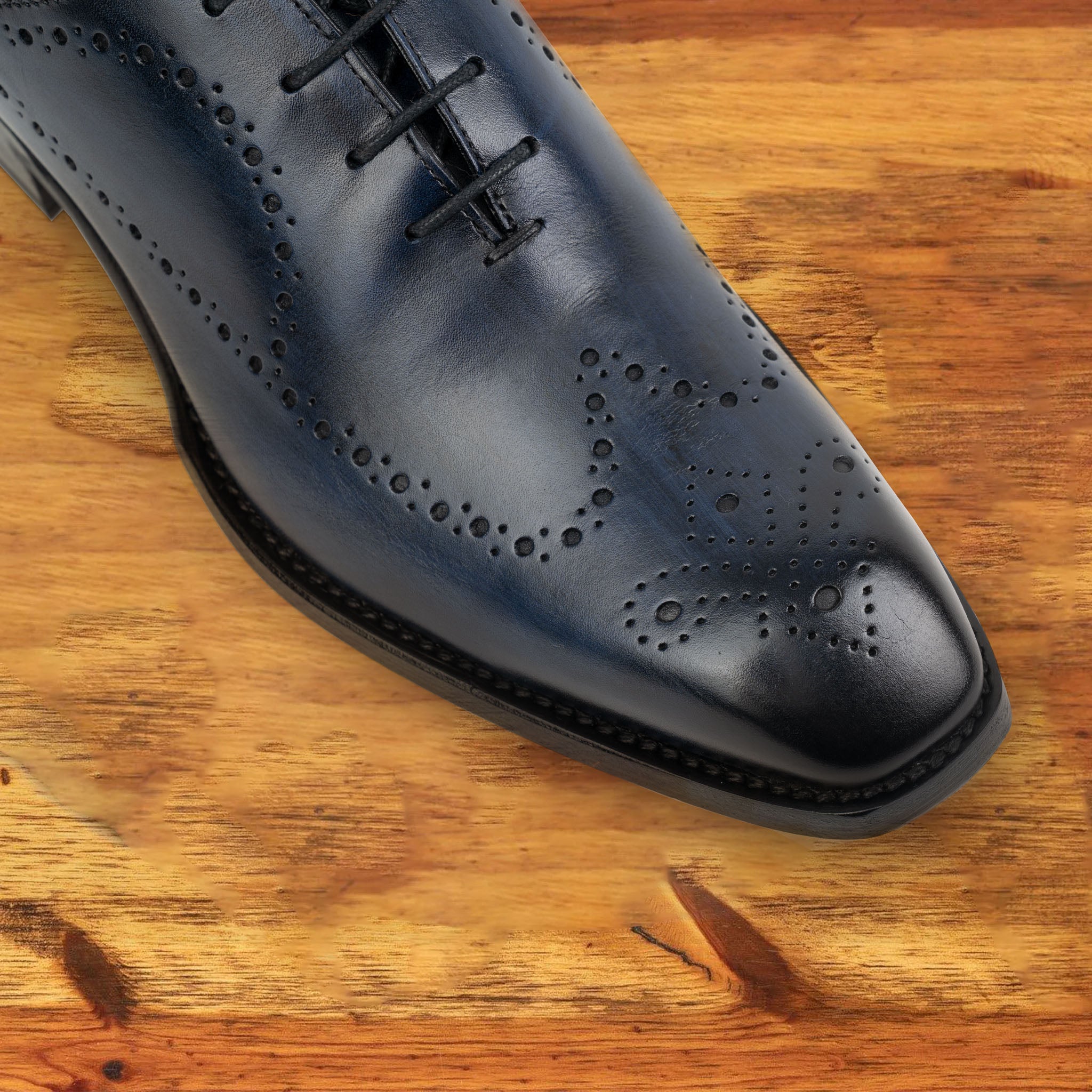 Black wholecut dress shoe on a wooden surface