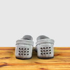 Pair of White loafer shoe on a wooden surface with a light gray background