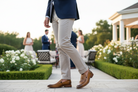 Man in a suit wearing Spice leather loafer walking outdoors with people and greenery in the background