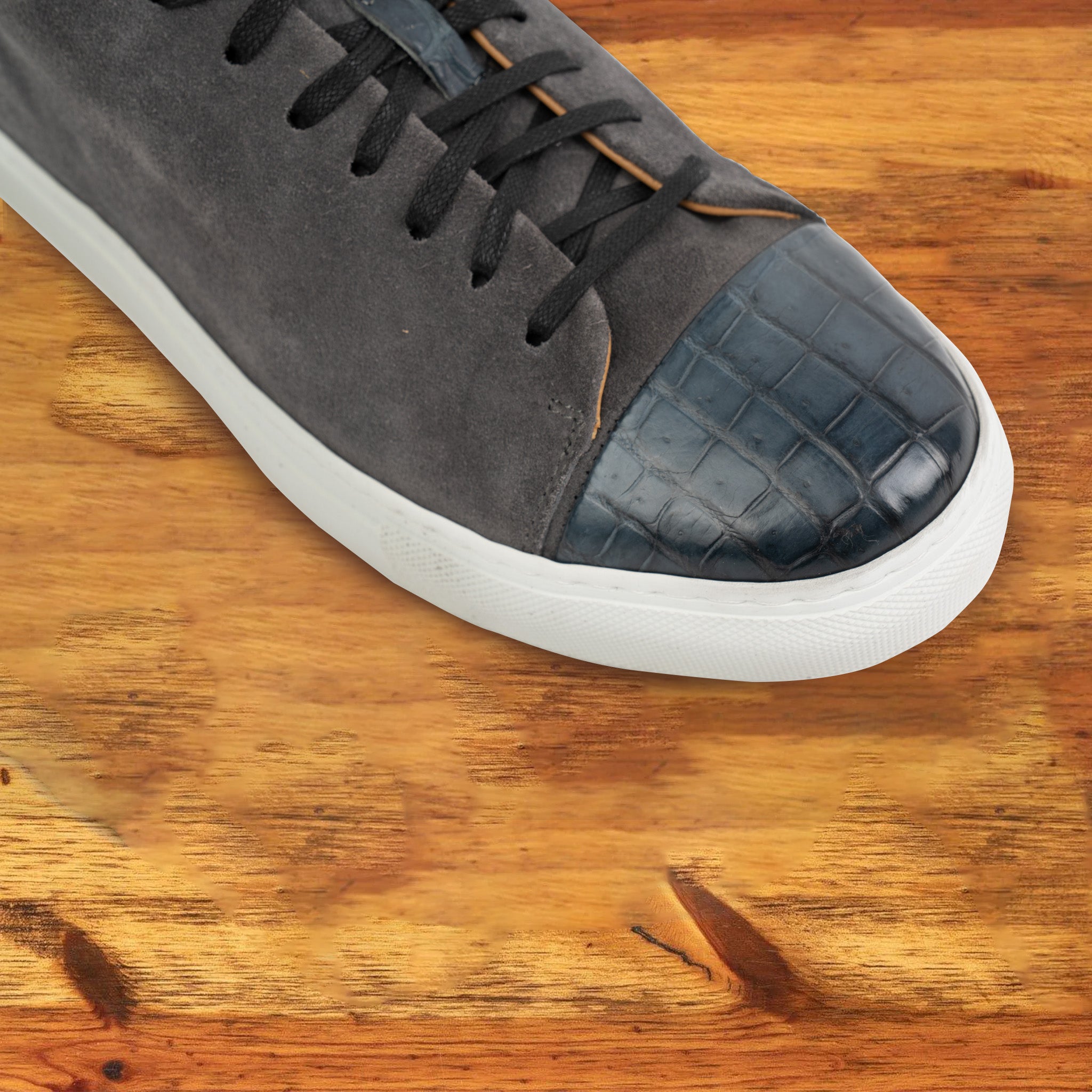 Gray suede sneaker with white sole on a wooden surface