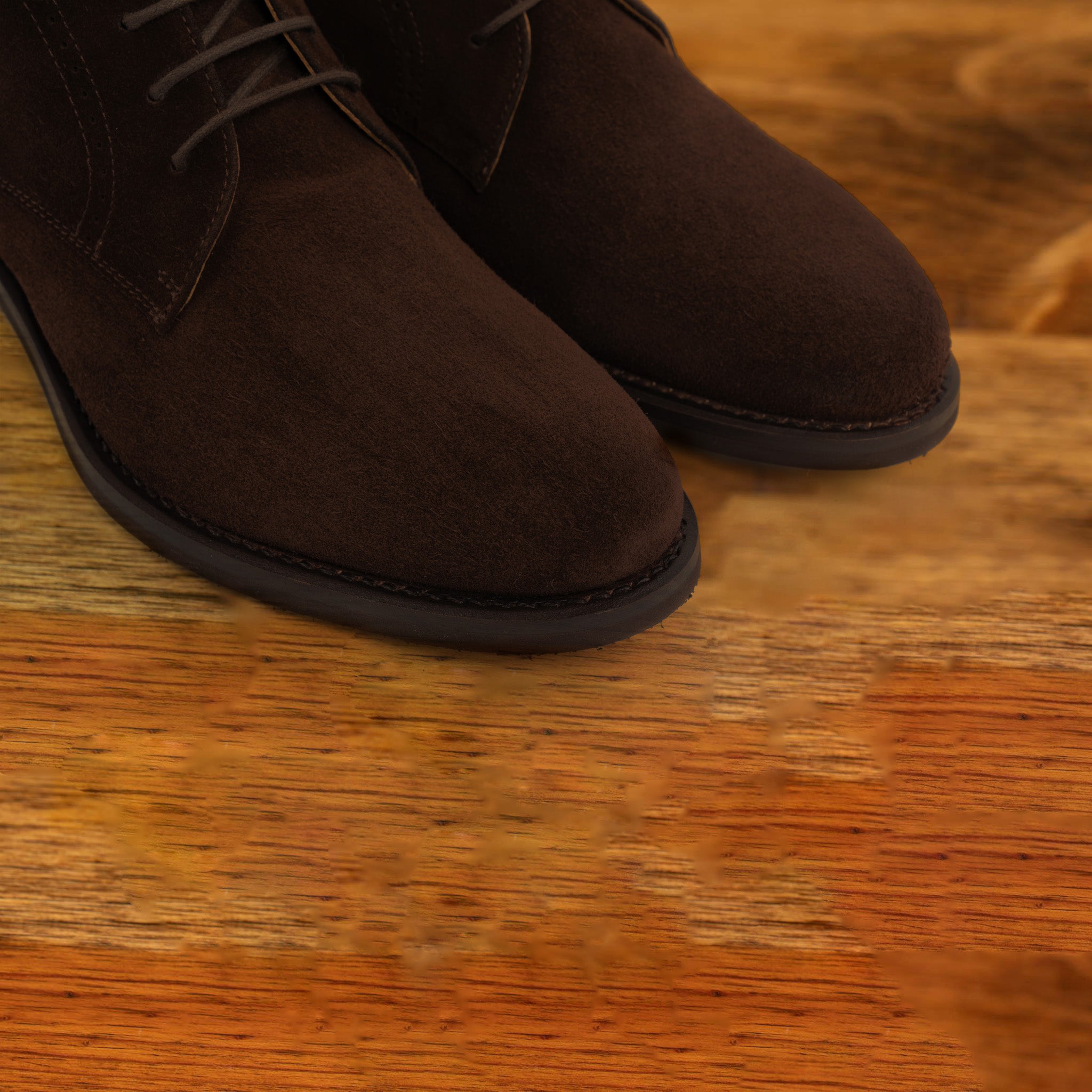 Pair of brown suede boots on a wooden surface
