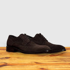 Pair of Brown suede dress shoe on a wooden surface with a light gray background
