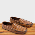 A Pair of Brick crocodile-patterned loafer on a wooden surface with a light gray background