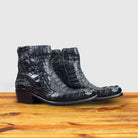 Pair of Black crocodile western boot on a wooden surface with a light gray background