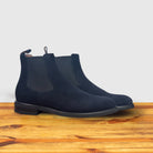 Pair of Navy blue Chelsea boot on a wooden surface with a light gray background