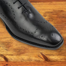 A Pair of Black wholecut dress shoe on a wooden surface