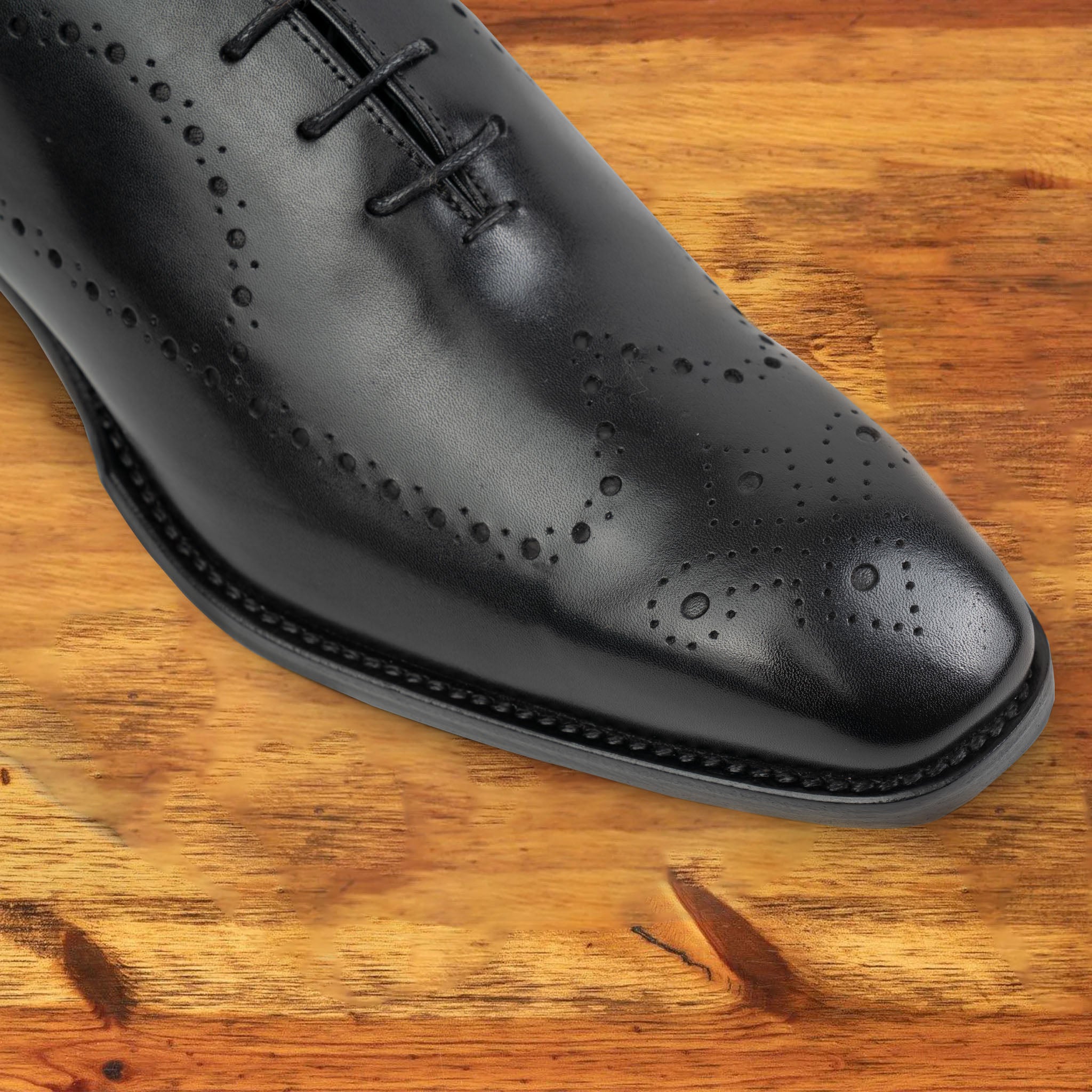 A Pair of Black wholecut dress shoe on a wooden surface