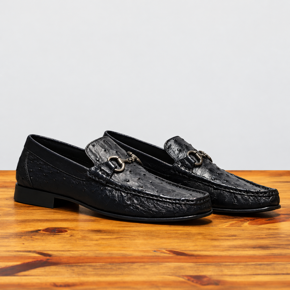 Pair of Black leather loafer on a wooden surface with a light gray background