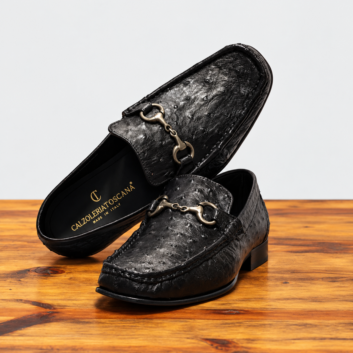 Pair of Black Ostrich Loafer on top of a wooden table