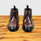 Pair of brown leather boots on a wooden surface with a light gray background