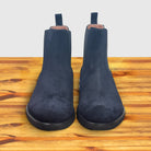 Pair of Navy blue Chelsea boot on a wooden surface with a light gray background