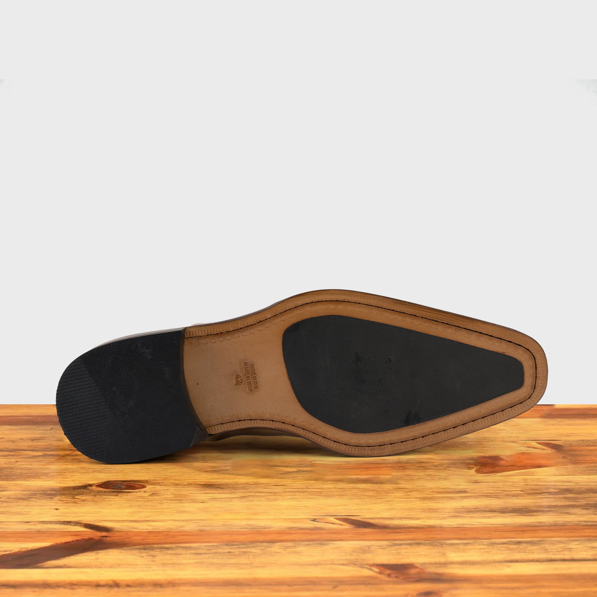 Outsole of Straw leather shoe on a wooden surface with a light gray background