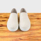 A Pair of White woven slip-on shoe on a wooden surface with a white background