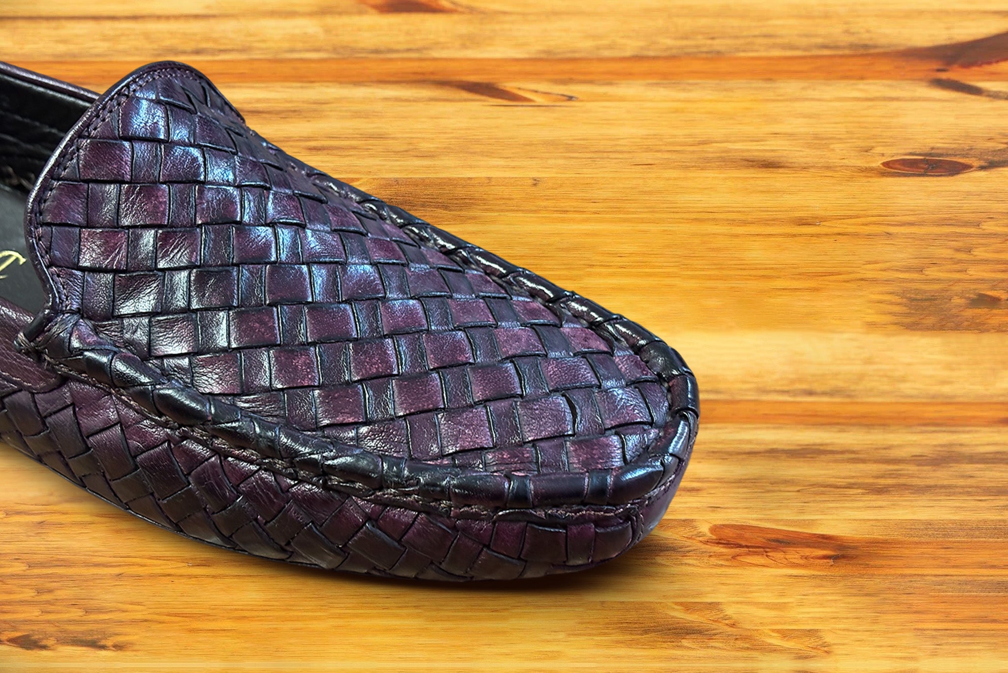 Merlot loafer shoe with woven pattern on a wooden surface