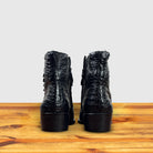 Pair of Black crocodile western boot on a wooden surface with a light gray background