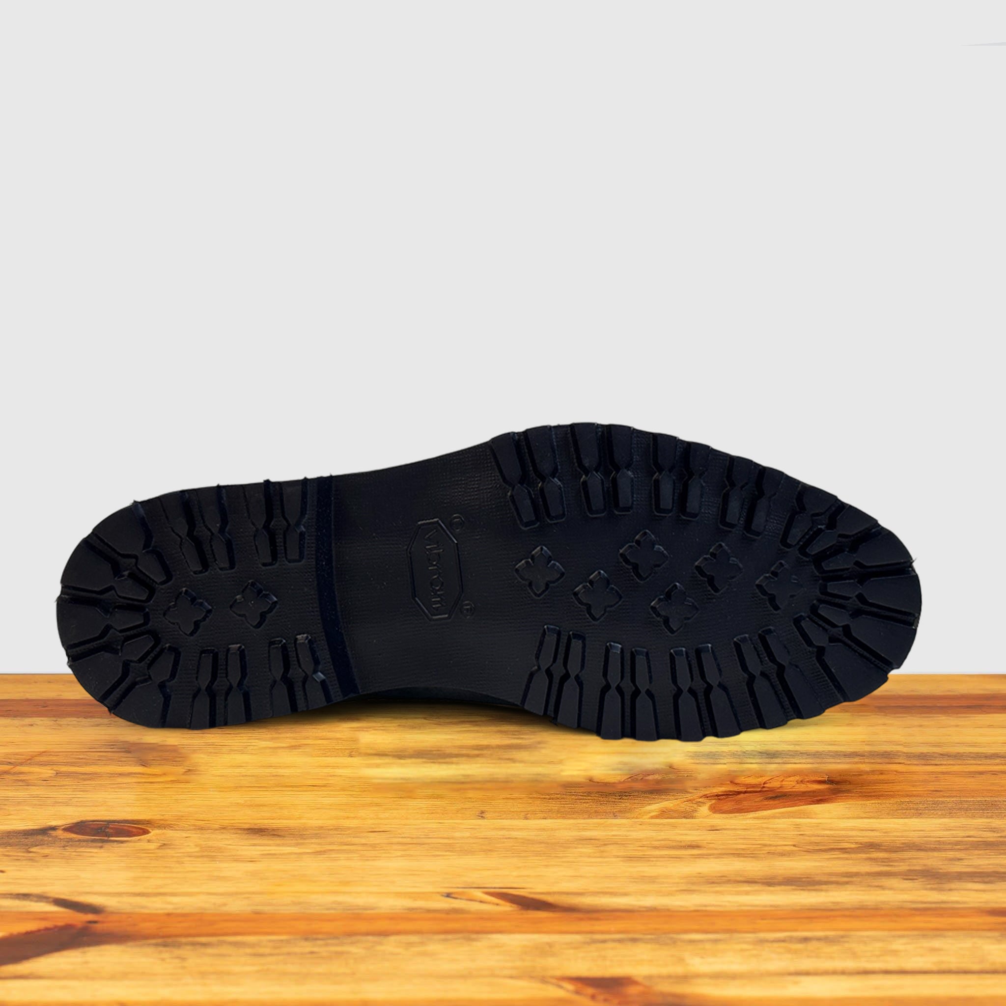 Outsole Stone leather Chelsea boots on a wooden surface with a light gray background